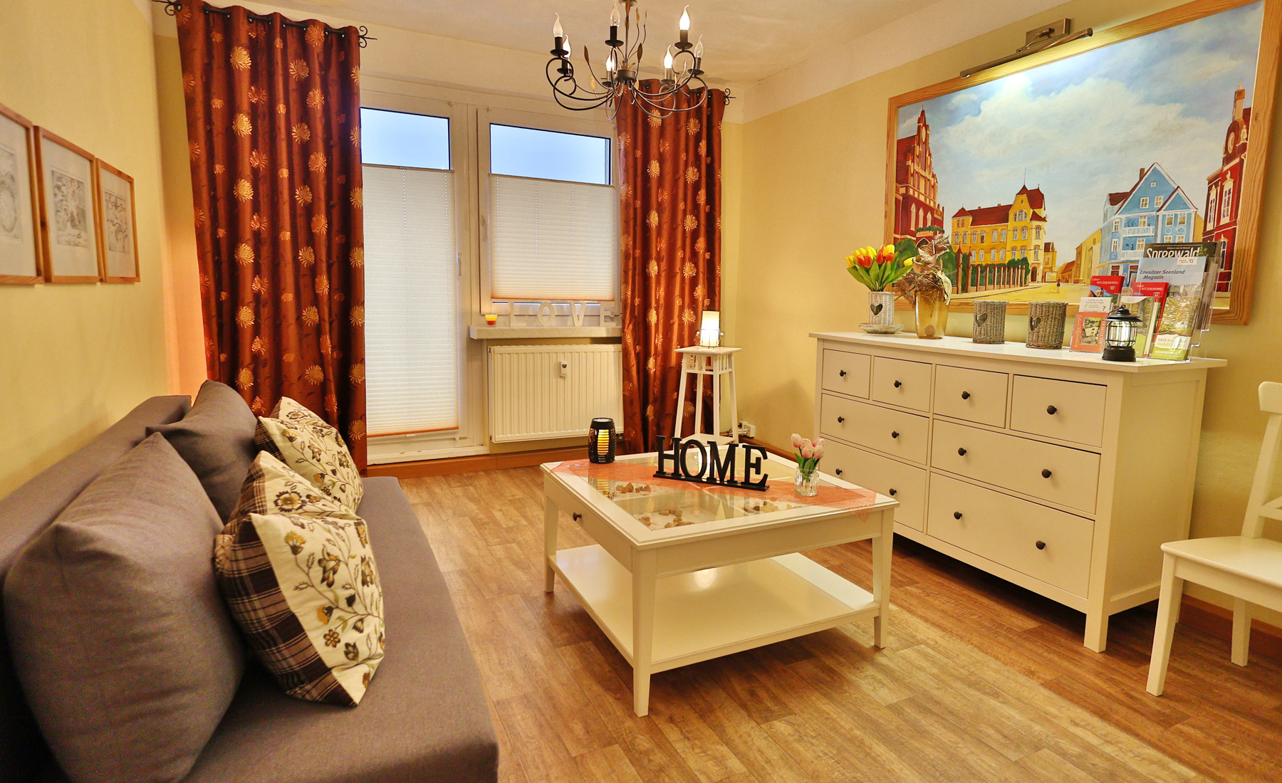 Gästewohnung Goldborn, Wohnzimmer mit Couch, kleiner Tisch und großem Bild an der Wand