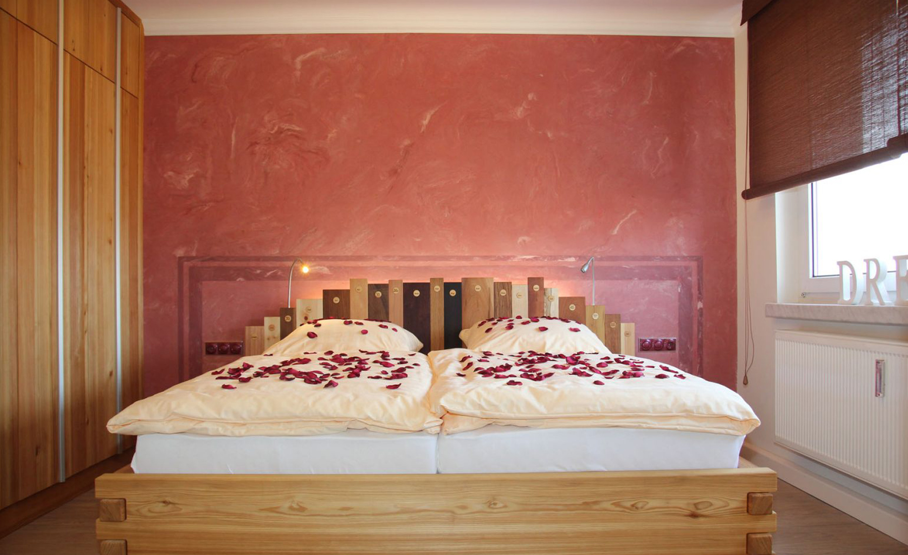 Gästewohnung Königsfarn, Doppelbett mit Rosenblütenblättern